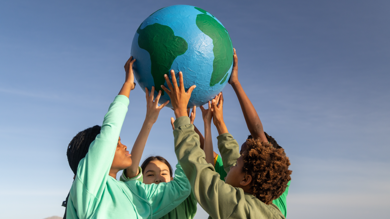 Kinder halten gemeinsam Weltkugel in die Höhe | © gettyimages | Alistair Berg