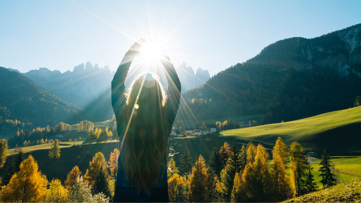 © Ascent/PKS Media Inc./Stone via Getty Images Frau greift nach der Sonne mit Blick auf Tal und Berge | © Ascent/PKS Media Inc./Stone via Getty Images